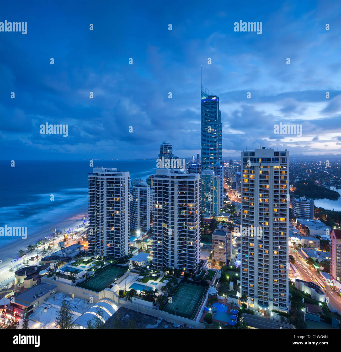 Blick über die moderne Stadt in der Abenddämmerung mit Ozean neben im quadratischen Format (Gold Coast, Queensland, Australien) Stockfoto