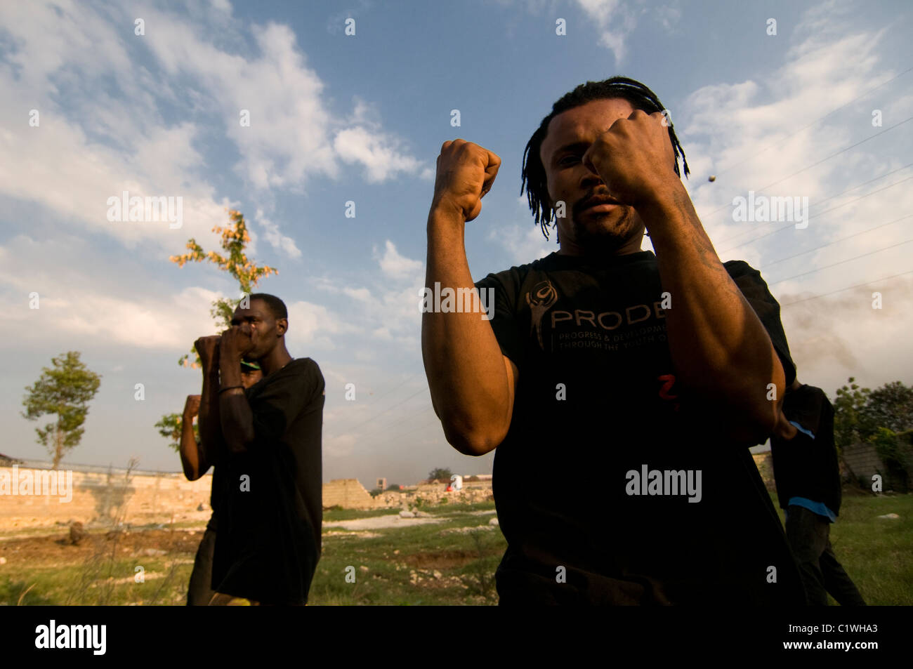 Haitianische Männer, die an einer Kampfkunst-Lektion teilnehmen, werden zu Sicherheitskräften einer provisorischen Wohnanlage in Port-au-Prince ausgebildet, die für Überlebende eines Erdbebens der Stärke 7,0 errichtet wurde, das Haiti am 12. Januar 2010 heimsuchte Stockfoto