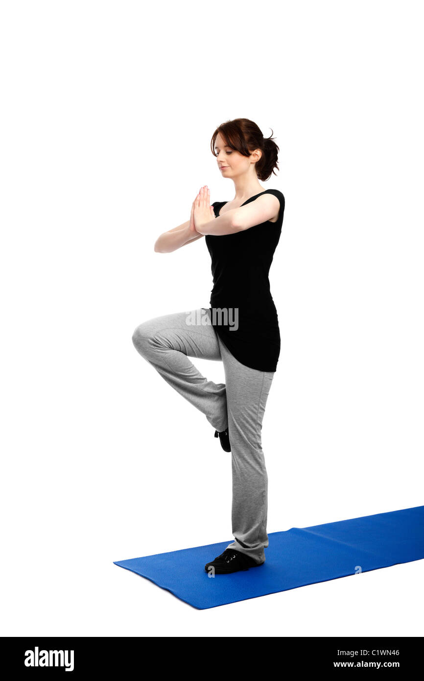 junge Frau, die Ausübung von Yoga auf einem Bein auf einem blauen Matte Stockfoto