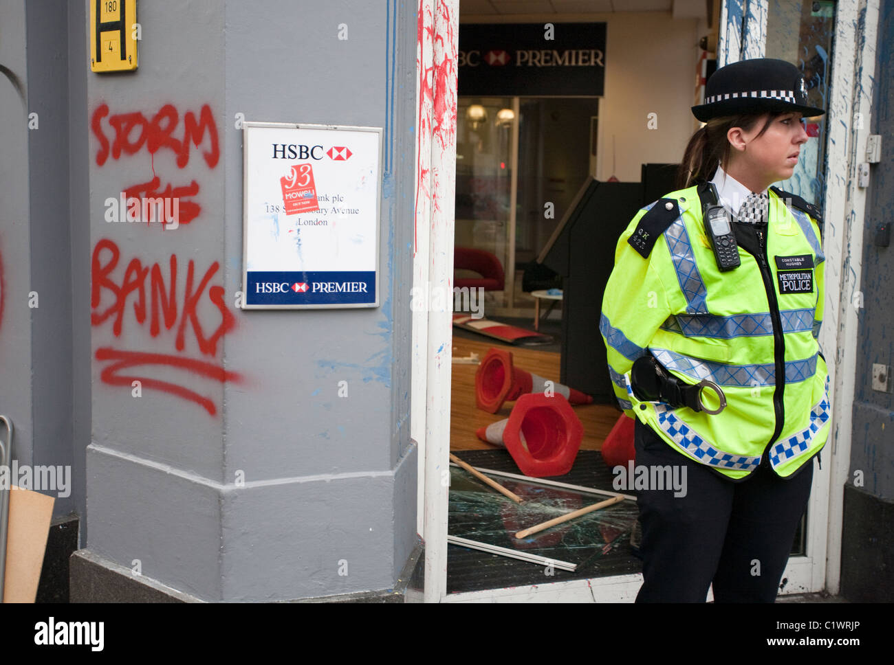 Polizistin steht Wache bei einer Filiale der HSBC Bank auf Cambridge Circus, kurz nachdem es von Anarchisten geplündert wurde. 26.03.2011 Stockfoto