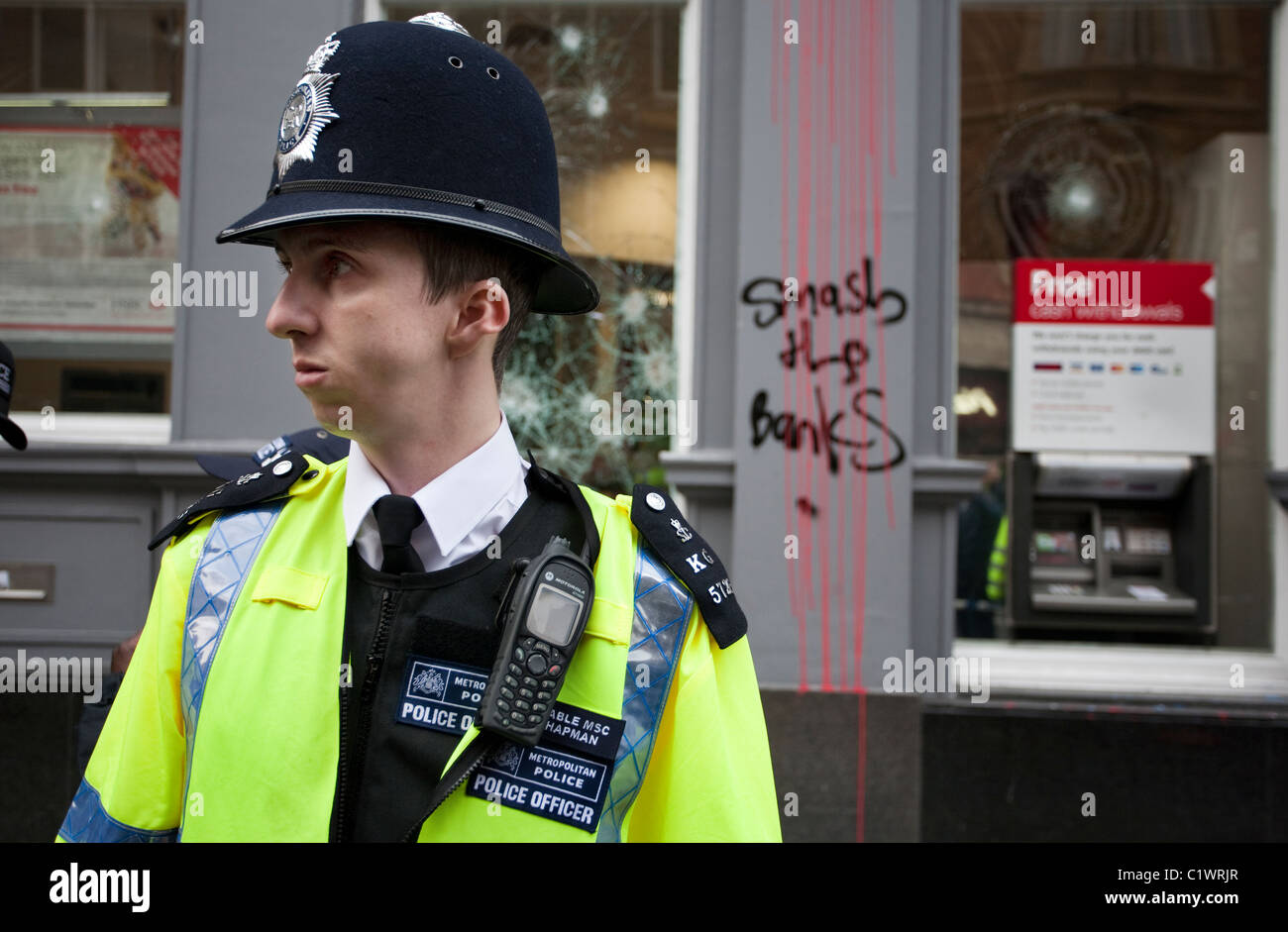 Polizist steht Wache bei einer Filiale der HSBC Bank auf Cambridge Circus, kurz nachdem es von Anarchisten geplündert wurde. 26.03.2011 Stockfoto