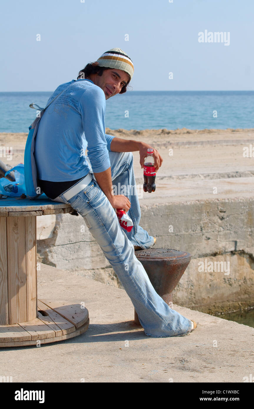 Ein Mann sitzt am Strand Rauchen und trinken Cola, Griechenland Stockfoto