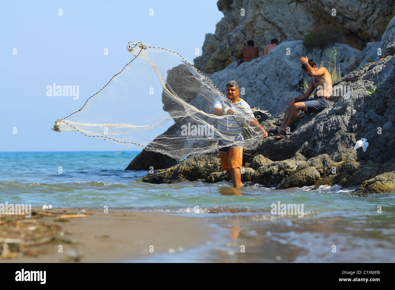Mann ein Fischernetz in der Mündung des Flusses fließenden Ägäische Meer zu werfen. Sarigerme, Mittelmeer, Türkei Stockfoto