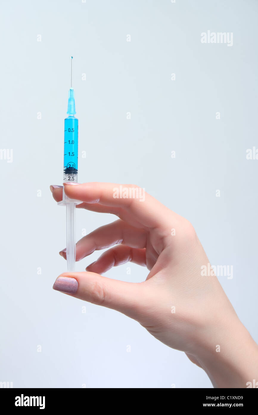 Frau hält in ihrer Hand medizinische Spritze mit blauen Lösung Stockfoto