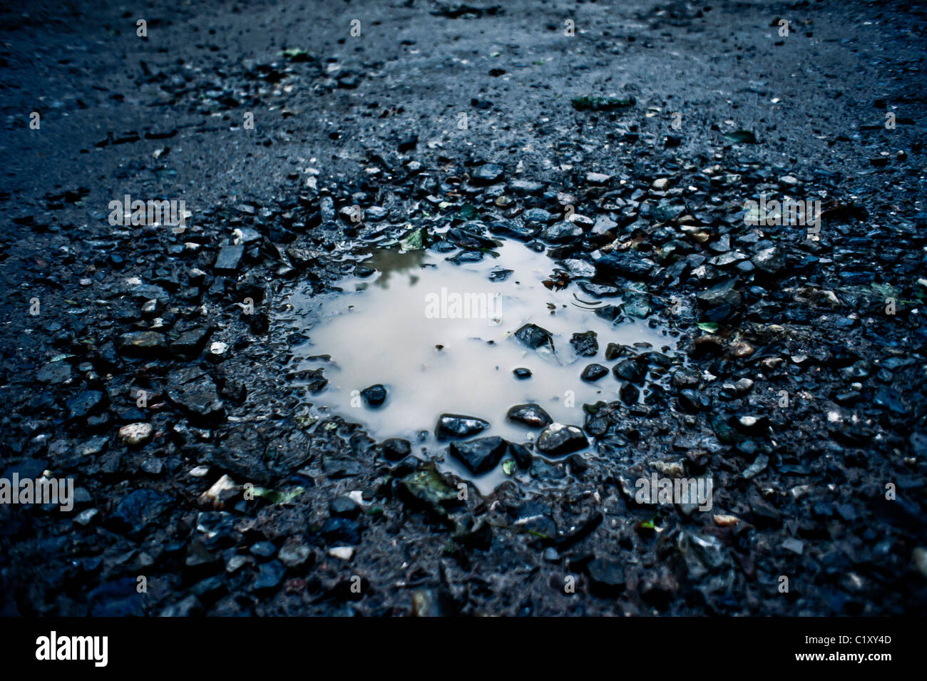 Ein Schlagloch in der Straße voll von Regenwasser Stockfoto