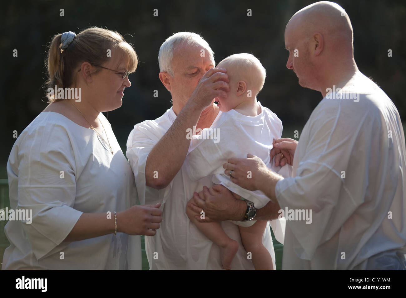 Ein Baby im Namen Gottes im Fluss Jordan getauft Stockfoto