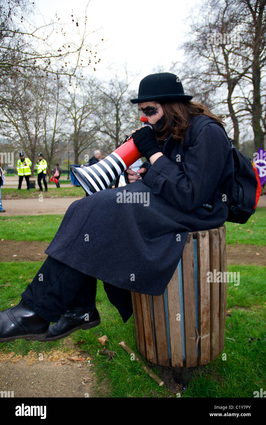 Mann in Make-up & Melone mit Megaphon auf Mülleimer im Park im März für die Alternative von der TUC, London organisiert Stockfoto