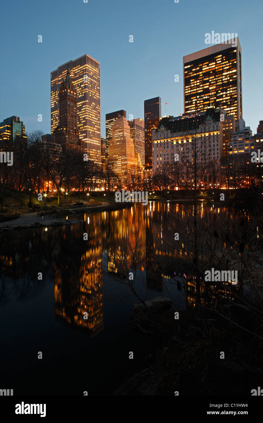 New York City-Blick auf das Plaza Hotel und andere Türme mit Reflexionen in den Teich von Gapstow Brücke im Central Park gesehen. Stockfoto
