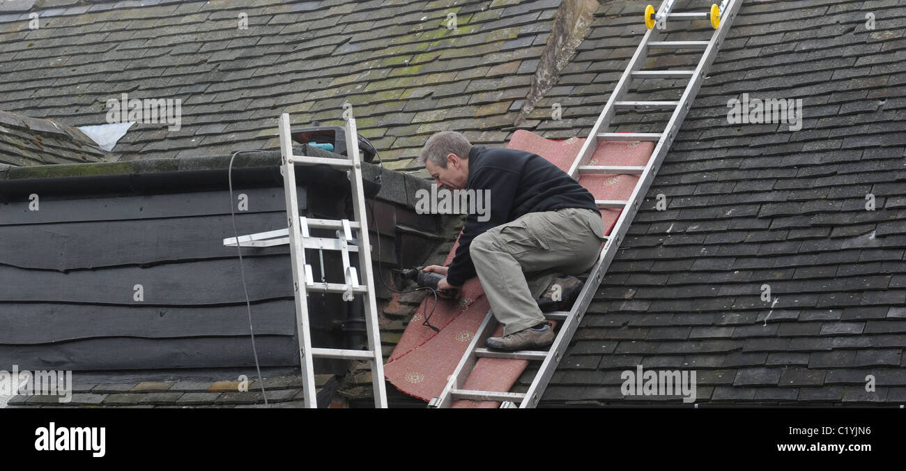 ARBEITER ARBEITEN AUF LEITERN AUF INLÄNDISCHEN HAUS RE DACH REPARATUREN DIGITALUMSTELLUNG NEUE ANTENNEN SIGNAL ANALOGABSCHALTUNG ETC. UK Stockfoto