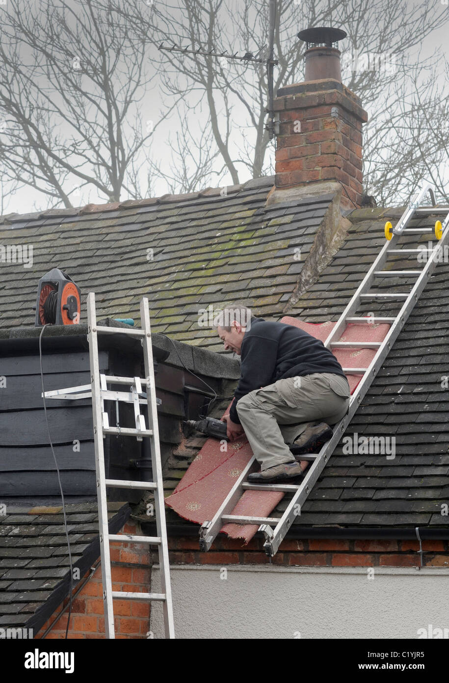 ARBEITER ARBEITEN VON LEITERN AUF INLÄNDISCHEN HAUS RE DACH REPARATUREN DIGITALUMSTELLUNG NEUE ANTENNEN SIGNAL ANALOGABSCHALTUNG ETC. UK Stockfoto