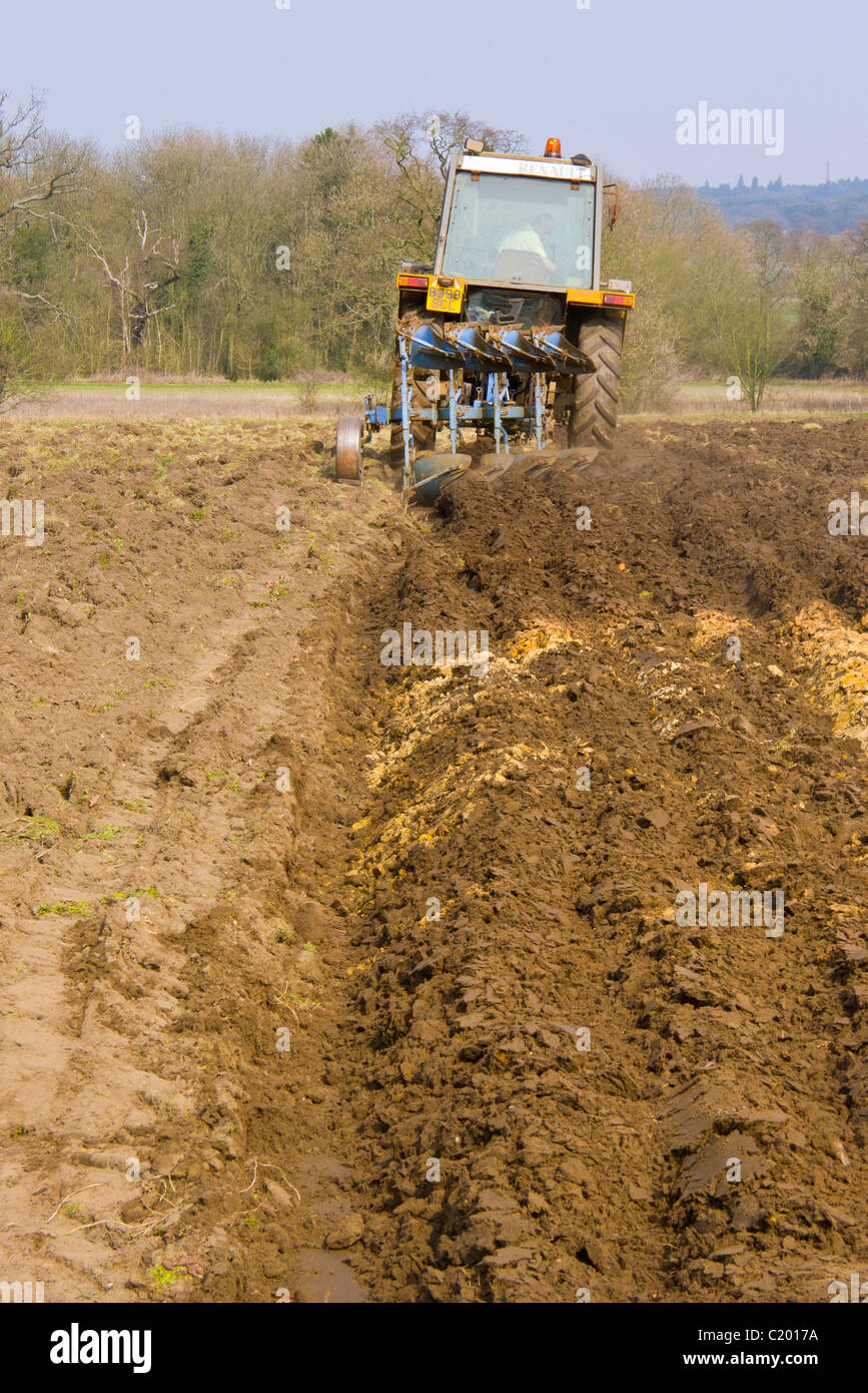 Mann in einem kleinen Traktor ein Feld mit einem Pflug Pflügen. Stockfoto