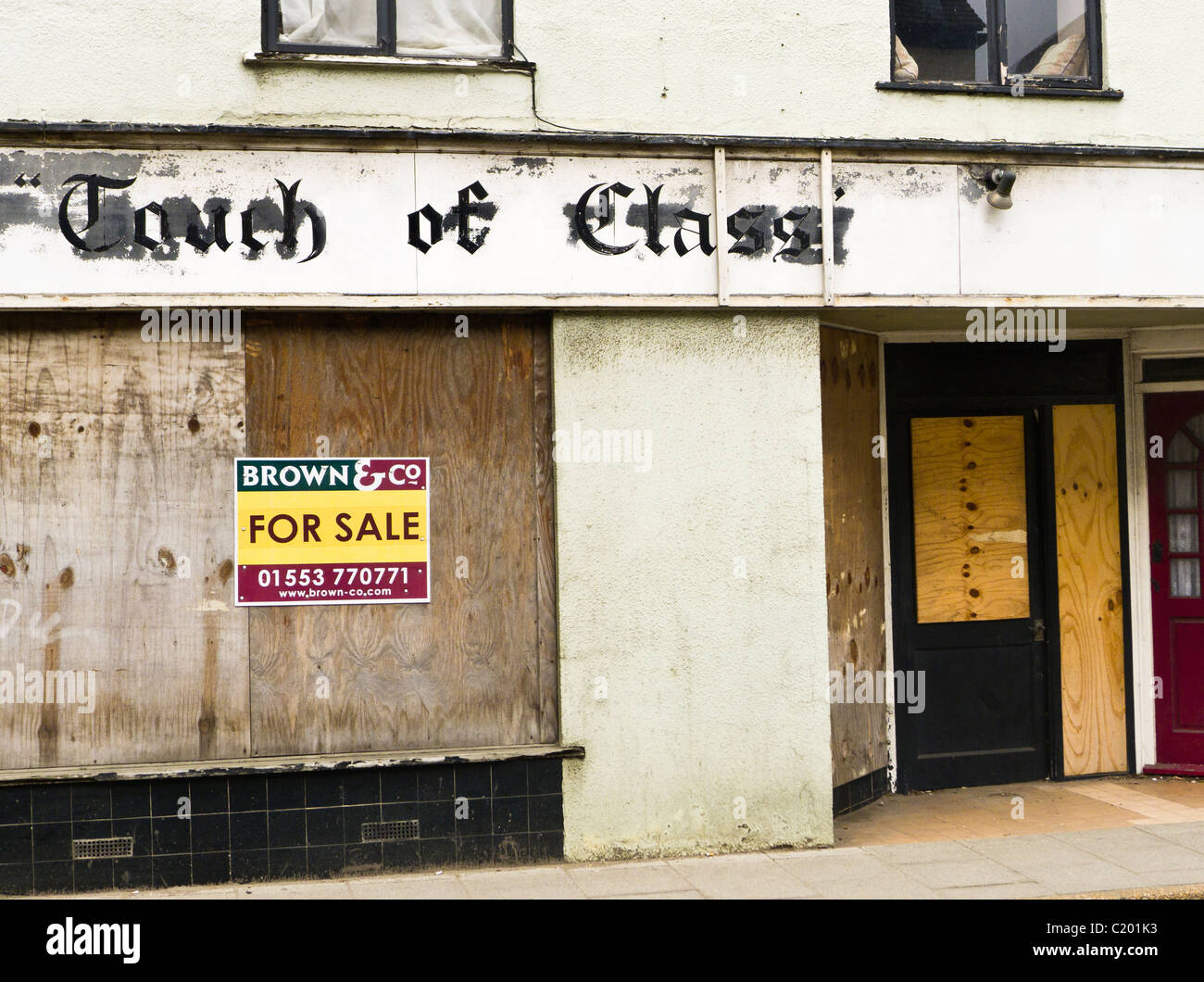 A mit Brettern vernagelt Ladenfront in King's Lynn zu verkaufen. Shop war "Touch of Class" genannt worden. Stockfoto