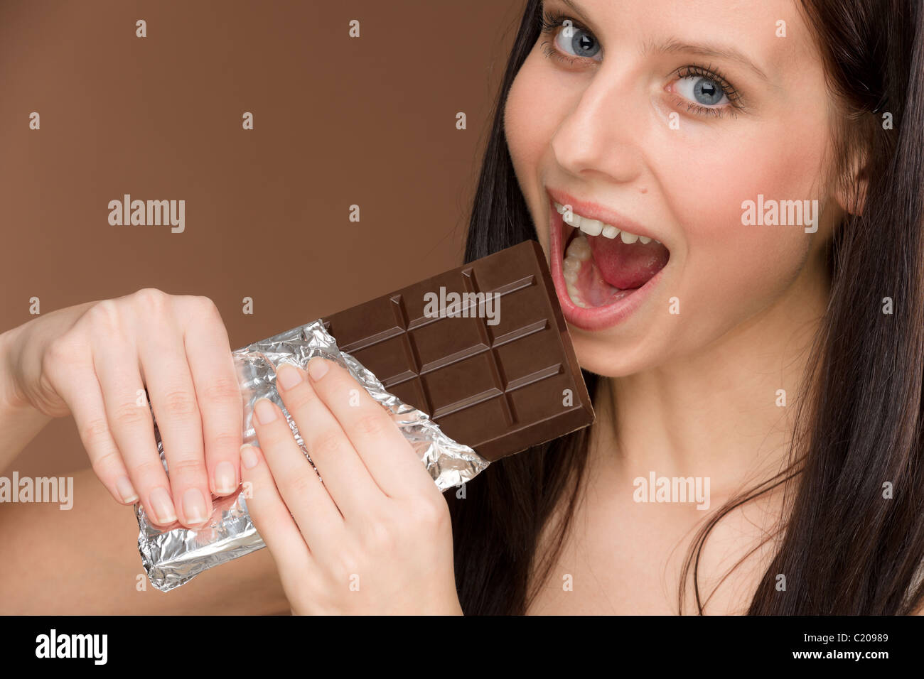 Schokolade - Porträt der jungen Frau Biss aus Süßigkeiten Stockfoto