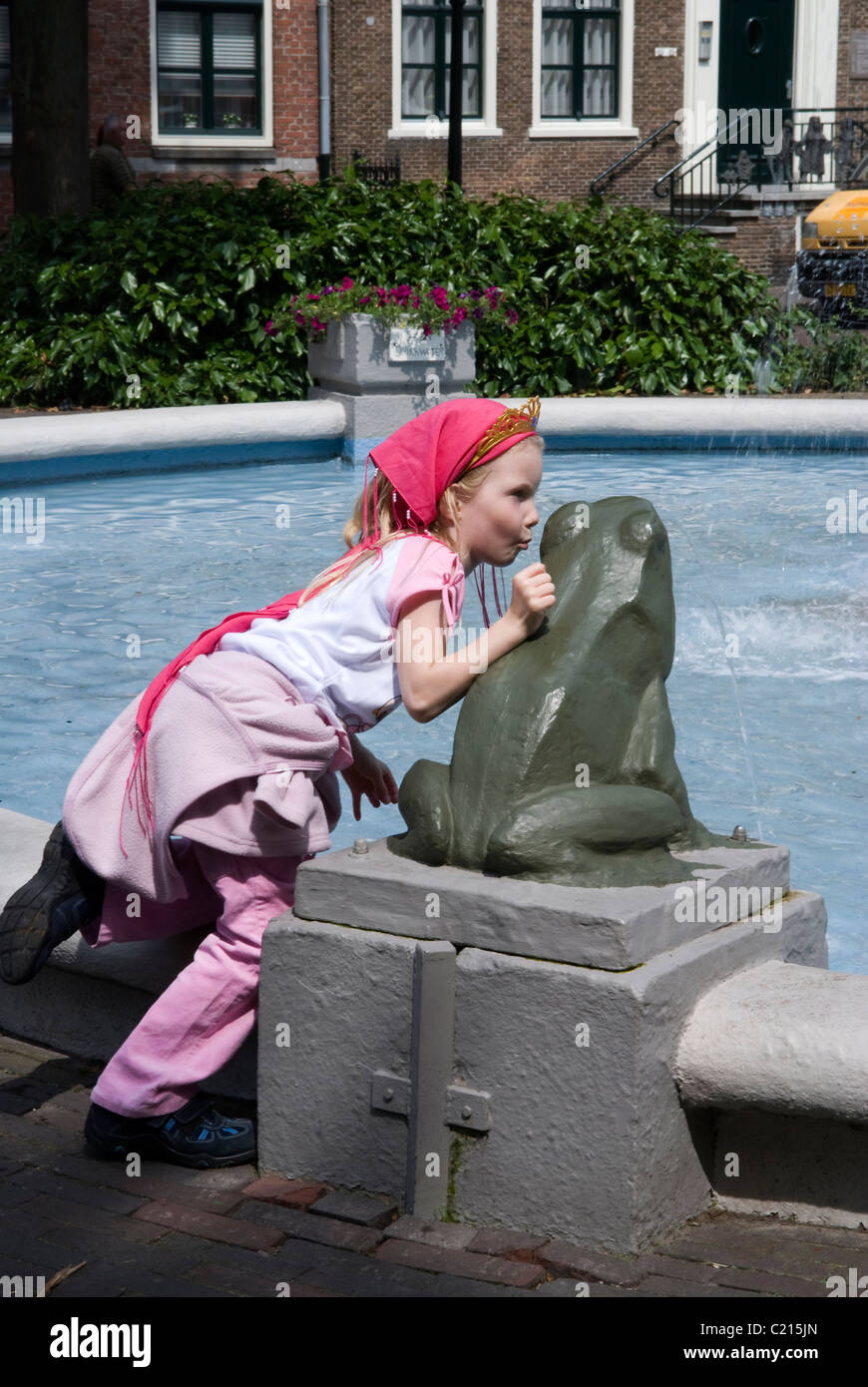 junges Mädchen küsst Frosch Skulptur Stockfoto