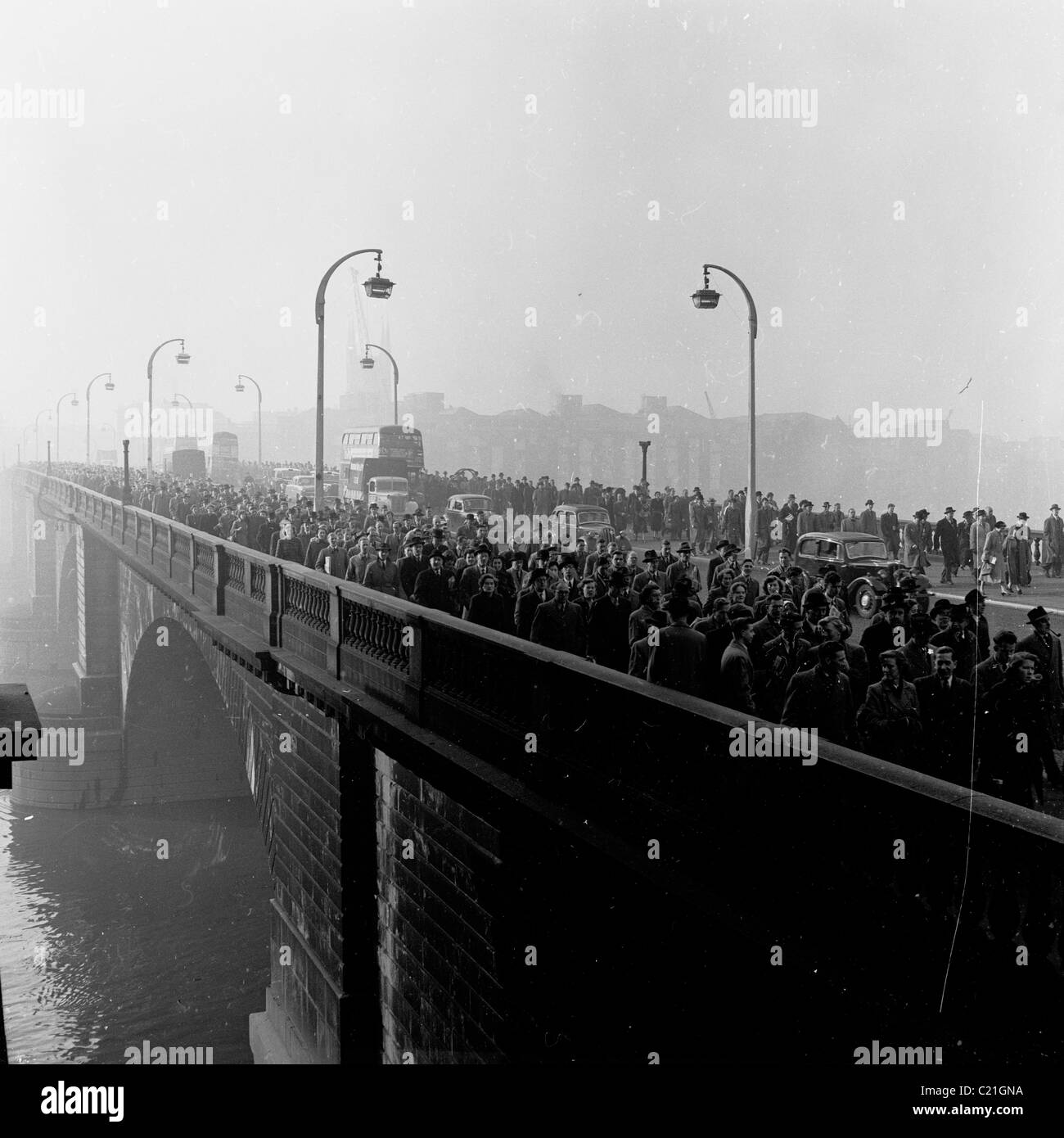 der 1950er Jahre eine versmogte London als große Massen von Menschen Fuß auf Waterloo Bridge, auf dem Weg zur Arbeit in diesem historischen Bild. Stockfoto