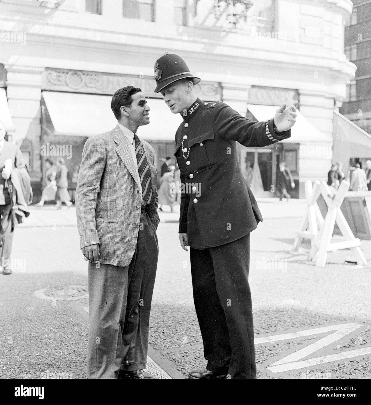 1950s, London, erhält ein neu angekommener Oveseas-Einwanderer nach Großbritannien Anweisungen eines britischen Polizisten, in diesem historischen Bild von J Allan Cash. Stockfoto