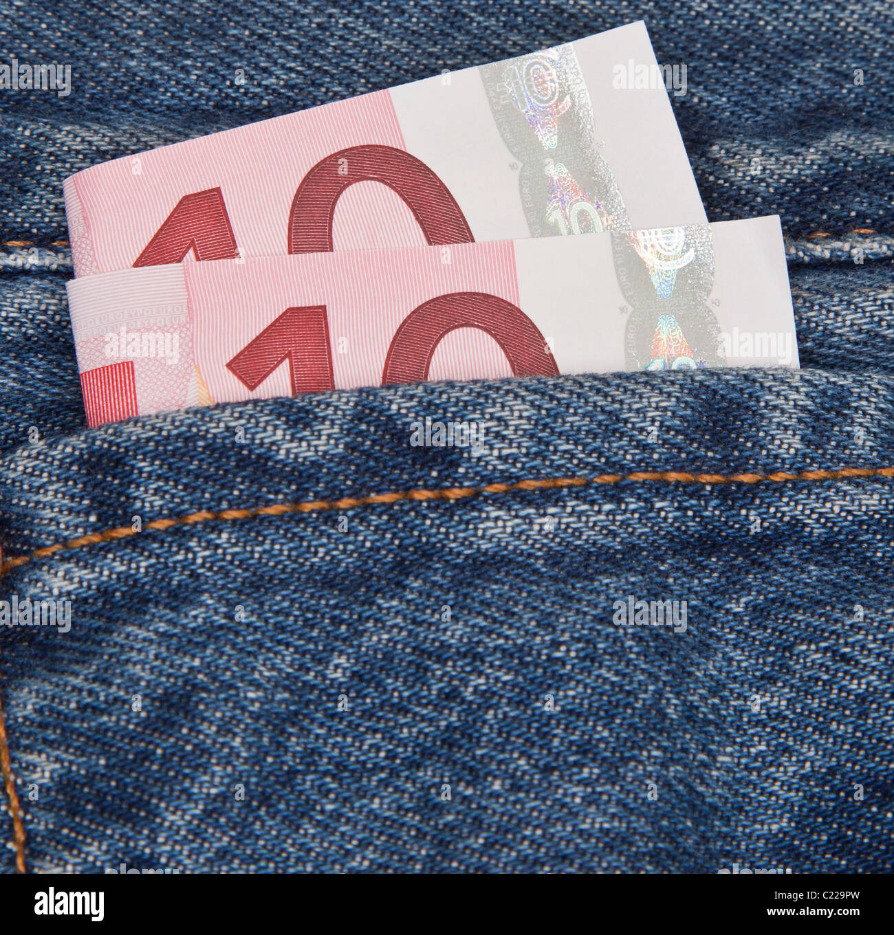 Zehn Euro-Noten ragen aus einer blauen Jeanstasche. Taschengeld. Verfügbares Einkommen. Stockfoto