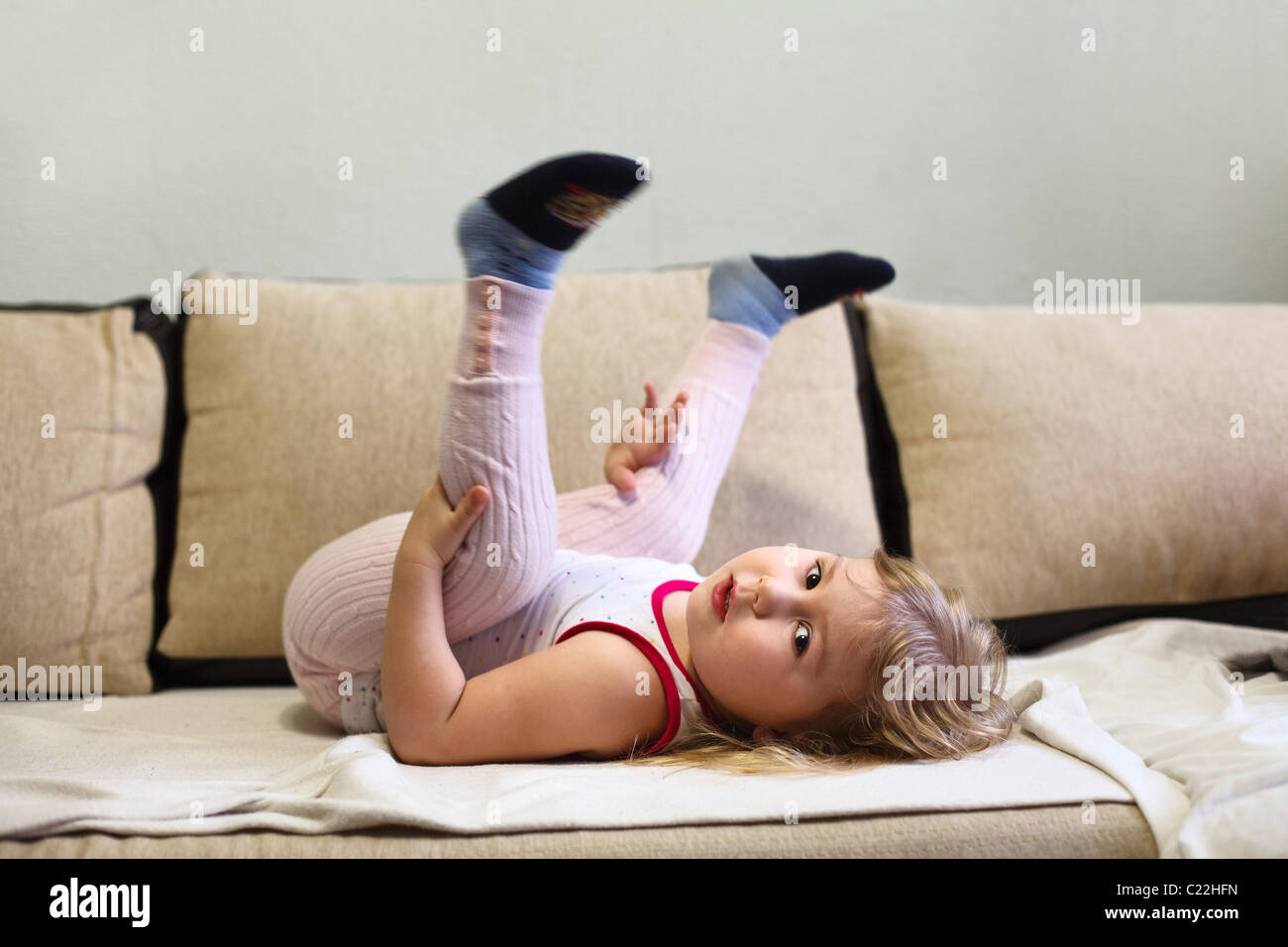 Das russische Mädchen liegt kopfüber auf einer Liege in einem Raum der Wohnung Stockfoto