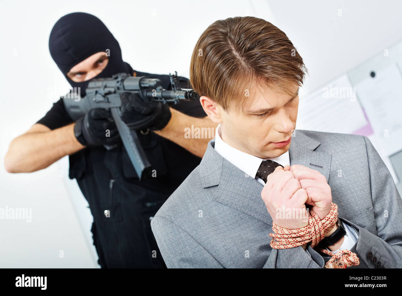 Porträt von verwirrt Geschäftsmann mit gefesselten Händen gejagt von Gangster zeigenden Waffe auf ihn Stockfoto