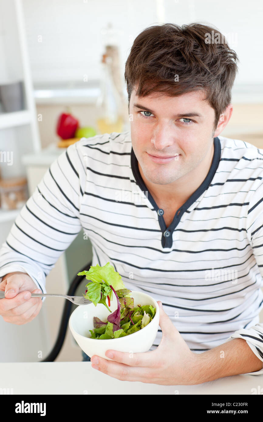 Hübscher junger Mann Essen einen gesunden Salat in der Küche Stockfoto