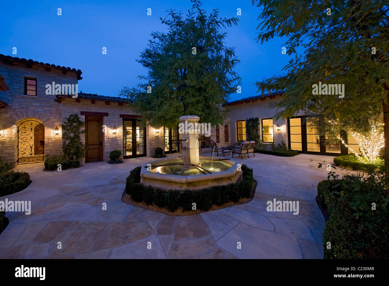 Haus außen in der Nacht mit einem Brunnen: Patio-Möbel und Bäume: ein in dem wird mit Lichterketten beleuchtet. Stockfoto