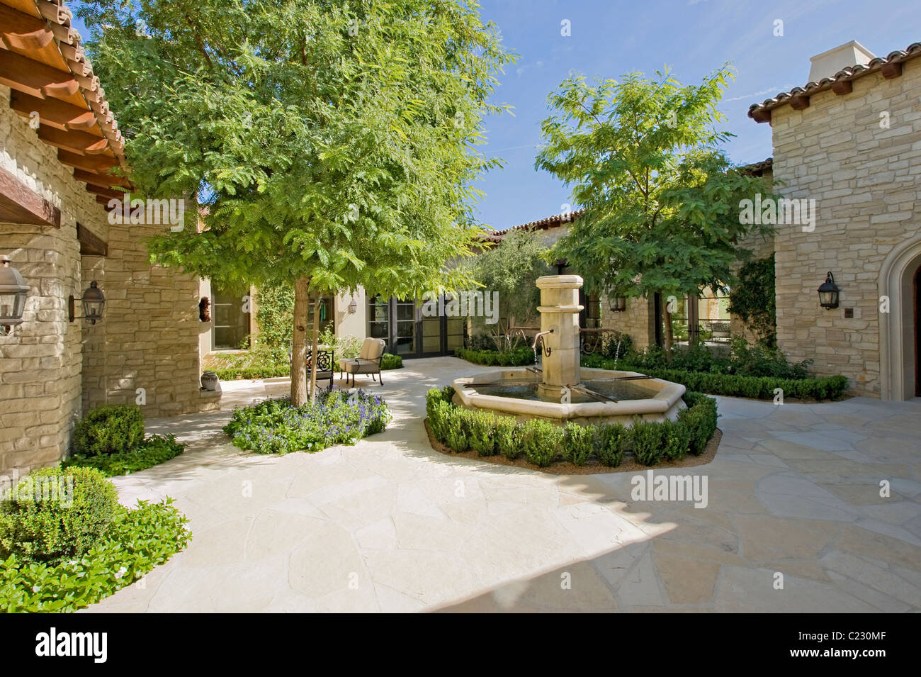 Haus außen bei Tageslicht mit einem Brunnen: Bäume und Pflanzen Stockfoto