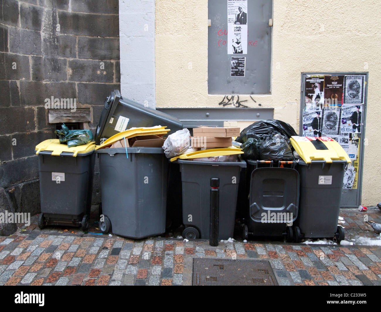 Volle Mülleimer entlang einer Wand in einer Stadt. Stockfoto