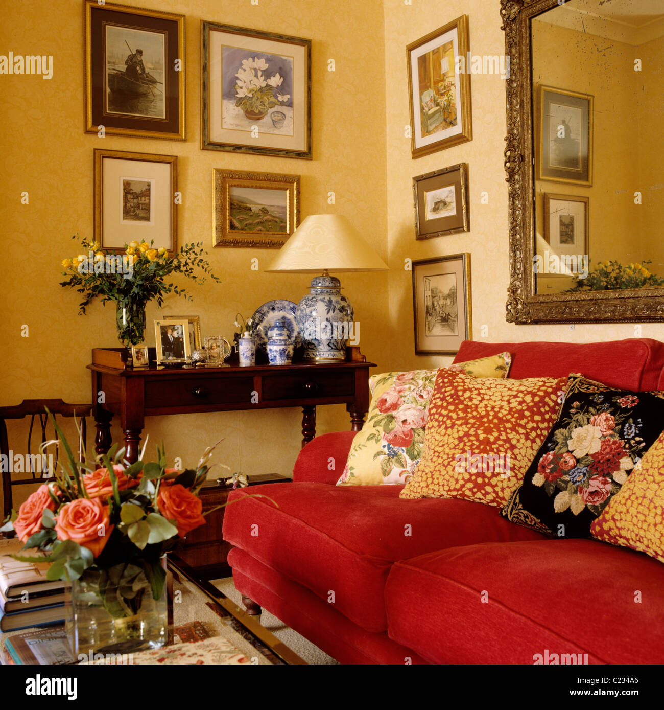 Gemusterte Kissen auf roten Sofa im Wohnzimmer mit einem traditionellen englischen Country-Interieur Stockfotografie