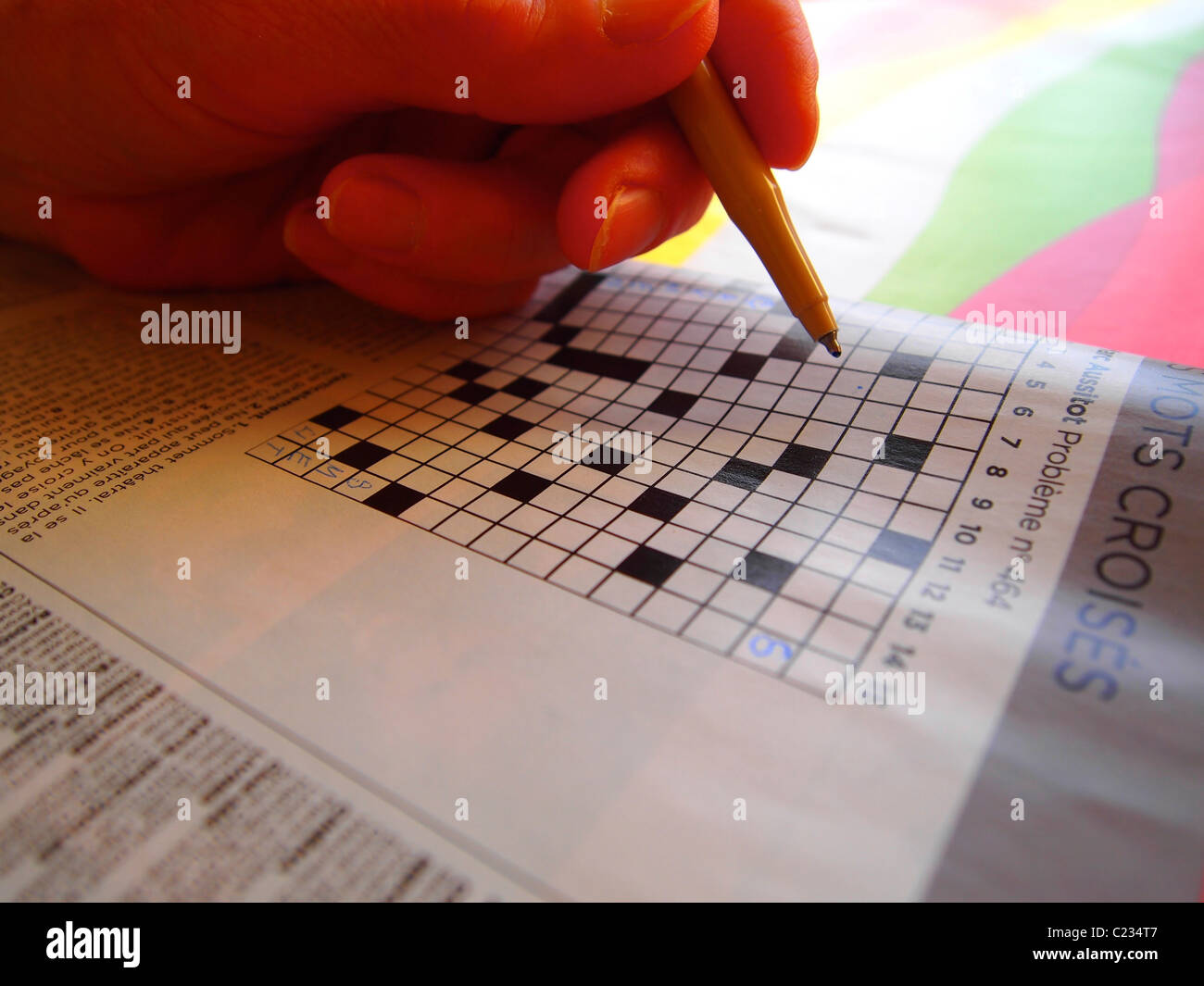 Machen Sie ein Kreuzworträtsel mit einem Stift auf einem farbenfrohen Hintergrund in der Freizeit Stockfoto