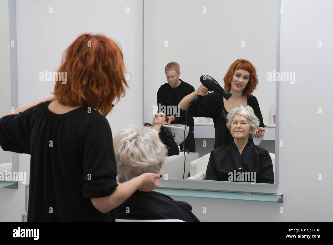 Stylist Schlag-trocknet ältere Frau an den Haaren Stockfoto