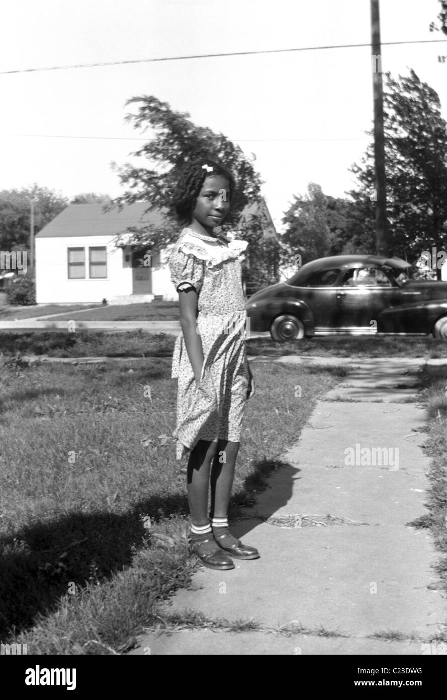 Sehr hübsches junges schwarzes Mädchen mit dem Familienauto im Hintergrund, Posen vor ihrem Haus in Washington Vororten, um 1950, USA Stockfoto