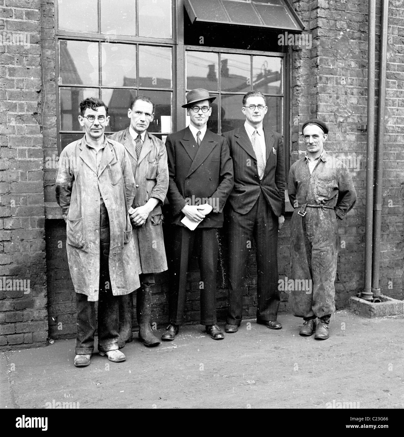 England der 1950er Jahre. Männliche Arbeiter und Management bei der jemals bereit Batterie Fabrik Line-up außerhalb des Gebäudes für ein Gruppenfoto. Stockfoto