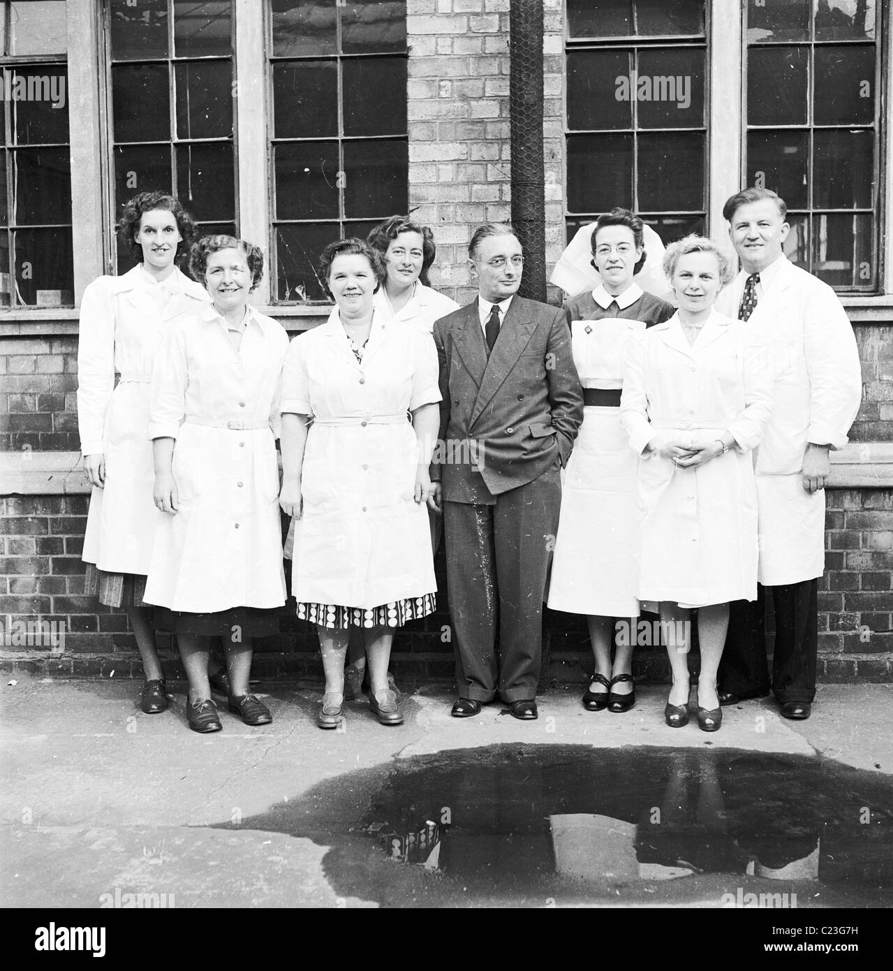 1950er-Jahre. Weibliche Fabrikarbeiter, eine Stationsschwester und männliche Manager an der stets bereit ist, Batterie in Forest Road, London, im Freien stehen für ein Gruppenfoto. Stockfoto