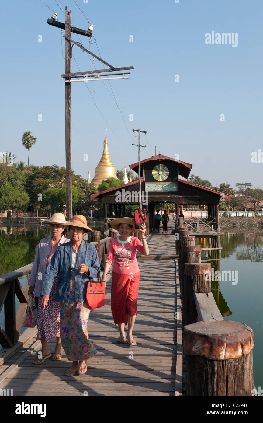 3 Frauen Ona Holzbrücke auf See mit Pagode in Mandalay bkgd.. Myanmar Stockfoto