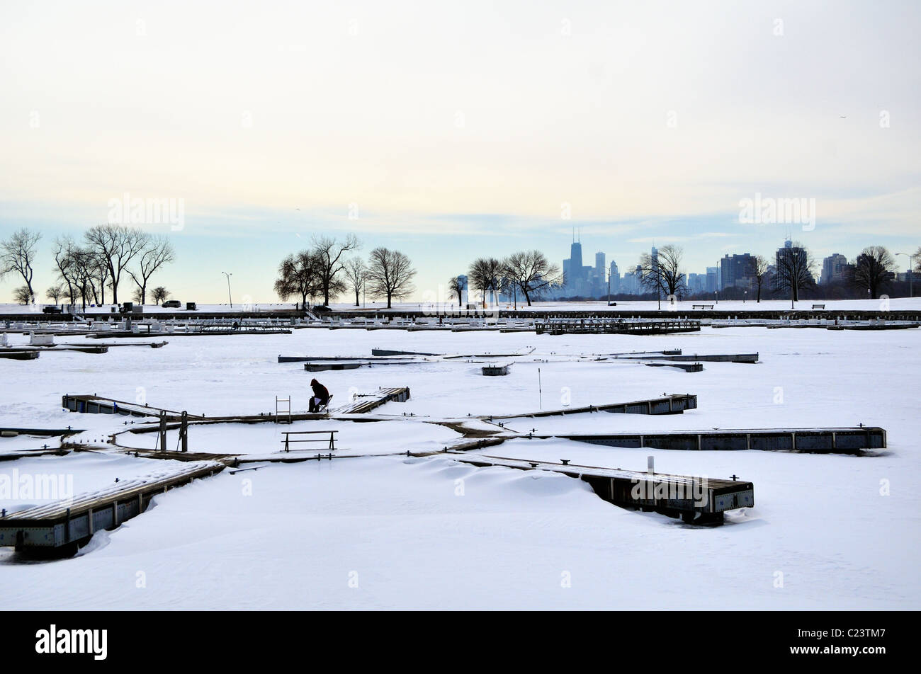 Einen einsamen Eis Fischer arbeitet seine Linie beim Sitzen auf dem gefrorenen Montrose Hafen. Chicago, Illinois, USA. Stockfoto