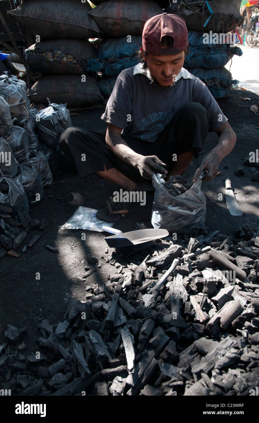 Junger Mann Gefühl Kunststoff Basg mit Holzkohle zu verkaufen. Mandalay. Myanmar Stockfoto
