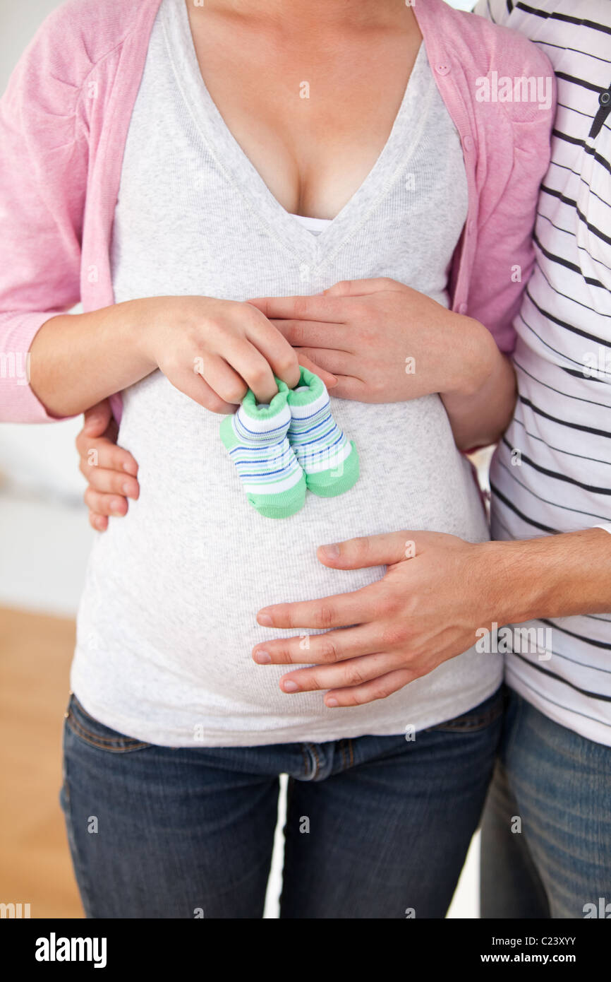 Nahaufnahme einer schwangeren Frau mit Babyschuhe und ihres Ehemannes Stockfoto