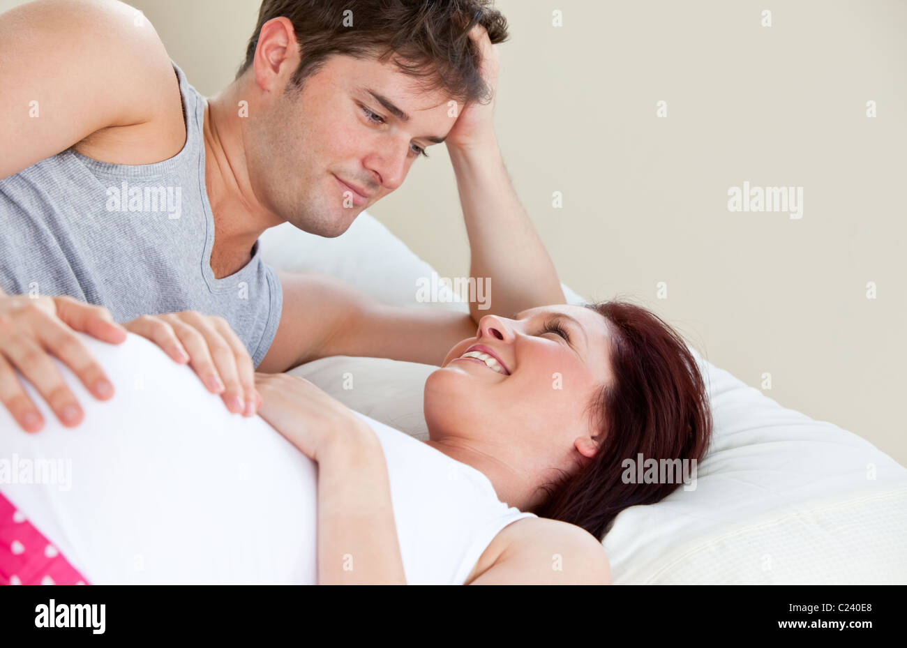 Porträt einer schwangeren Frau und des Mannes auf dem Bett liegend Stockfoto