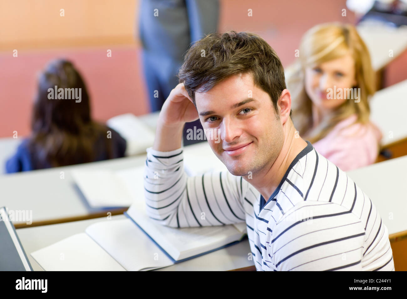 Freudige männlichen Studenten lächelnd in die Kamera während einer Universität-Lektion Stockfoto