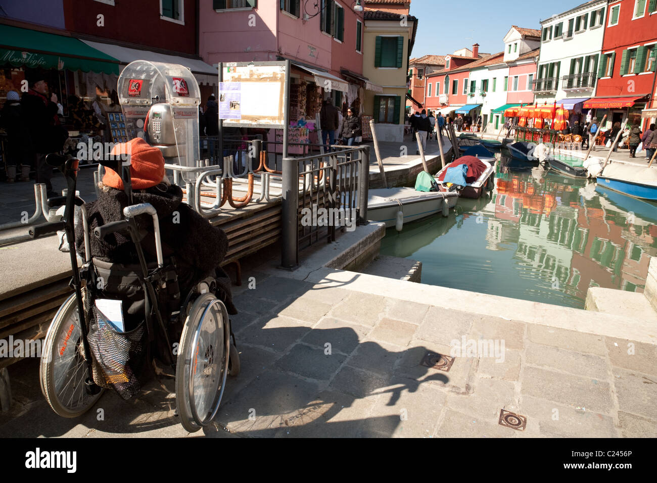 Eine behinderte Frau in einem Rollstuhl durch den Kanal genießen die Sonne in Burano Dorf, Venedig, Italien Stockfoto
