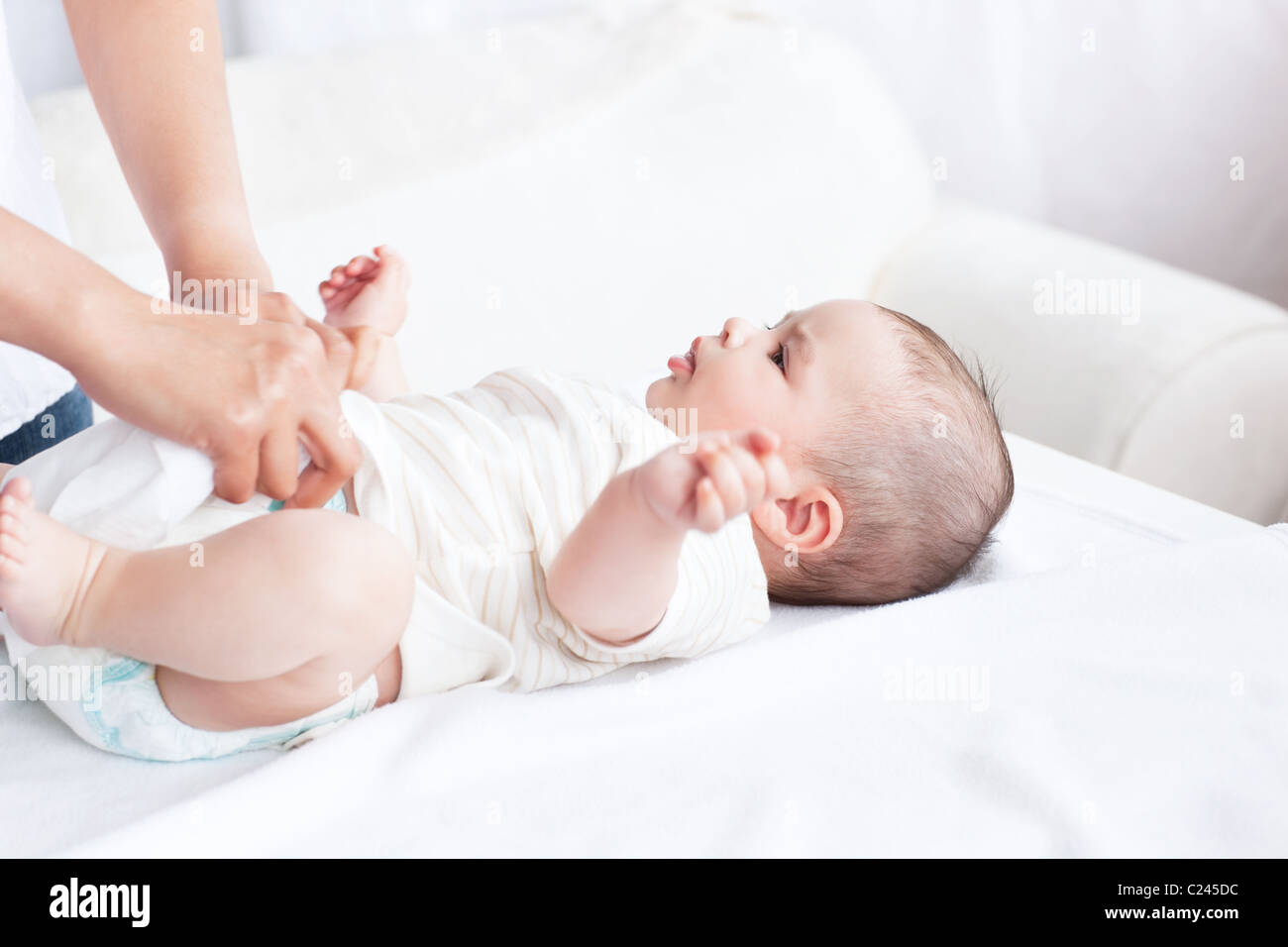 Nahaufnahme einer jungen Mutter die Windel ihres Babys auf einer Couch ändern Stockfoto