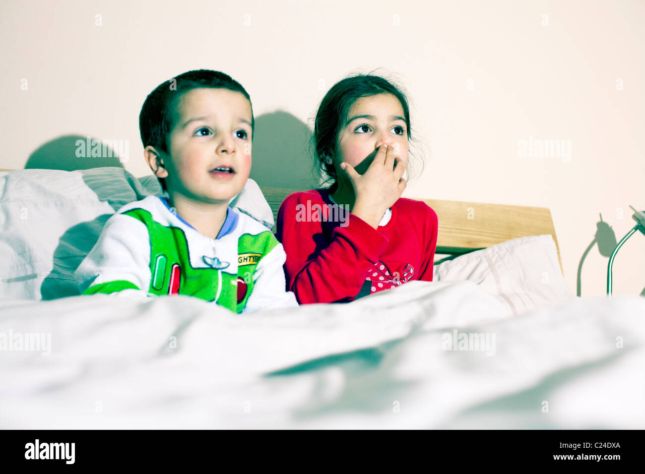 Geschwister vor dem Fernseher im Bett Stockfoto