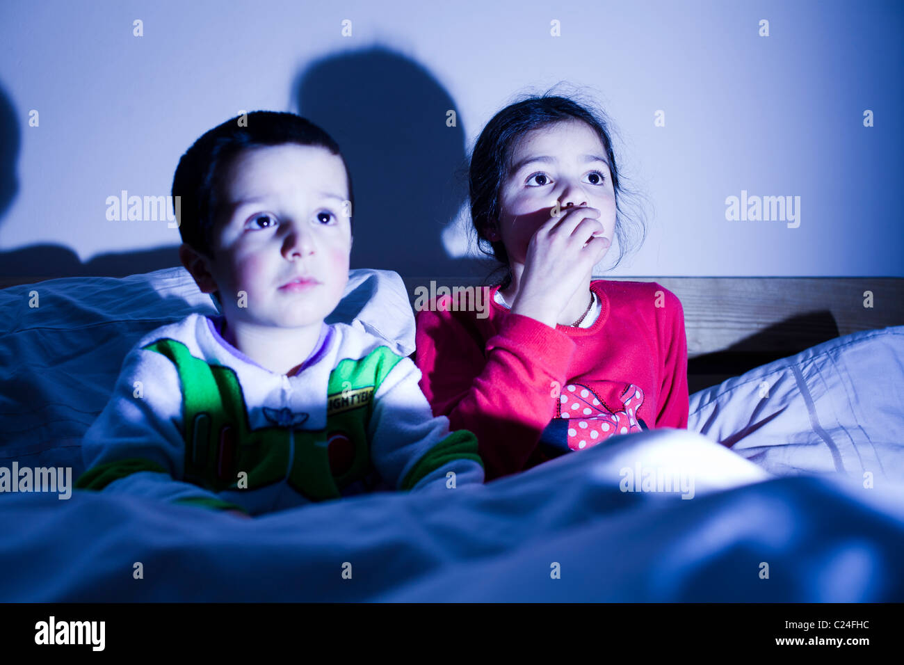 Geschwister vor dem Fernseher im Bett zusammen Stockfoto