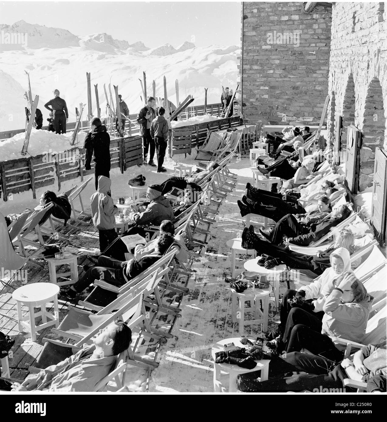 Frankreich, 1950er Jahre. Skifahrer, die sitzen in Liegestühlen außerhalb in einem Skigebiet in Frankreich, Stockfoto