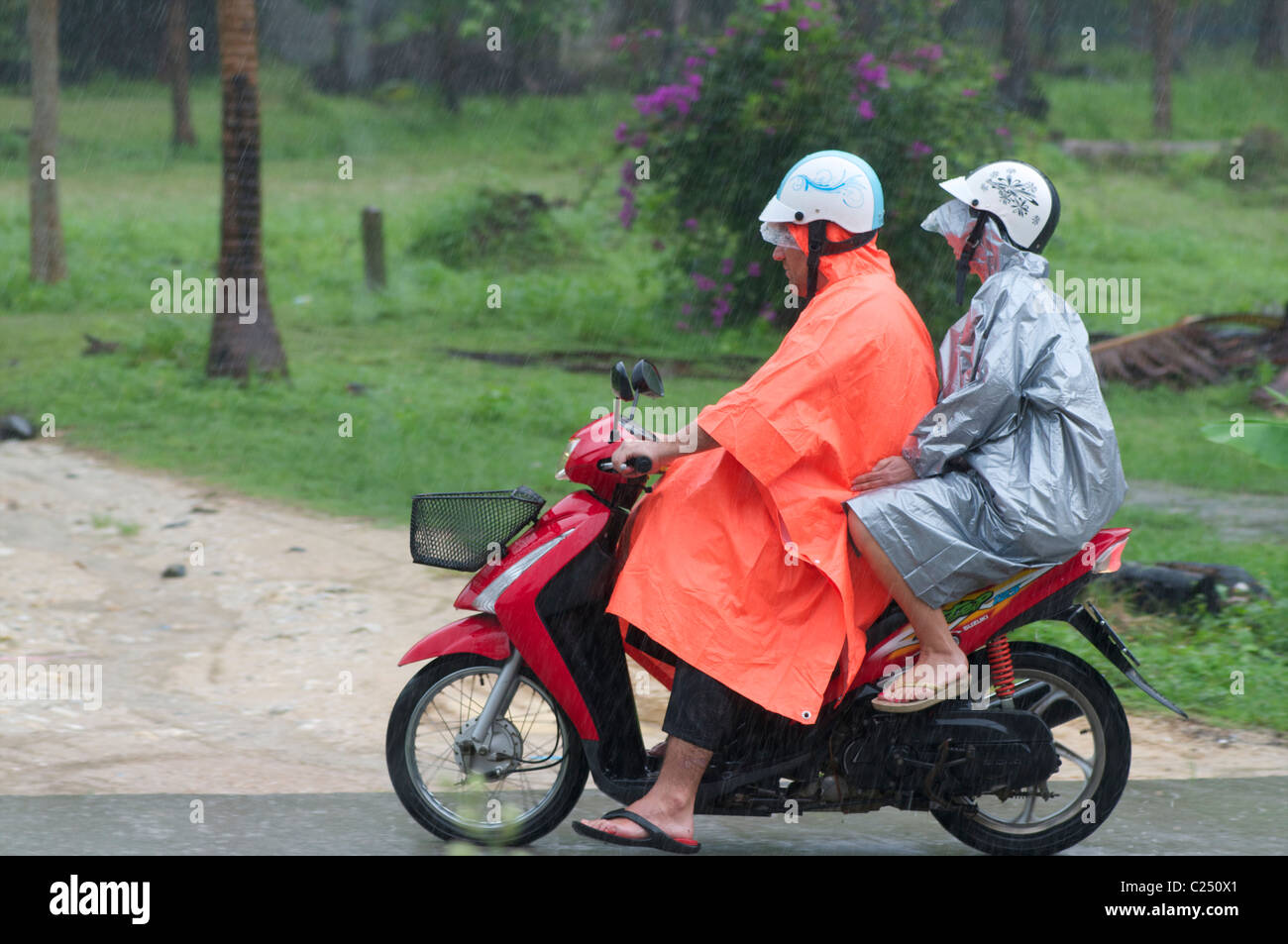 Touristen in Regenmäntel auf einem Motorrad Stockfoto