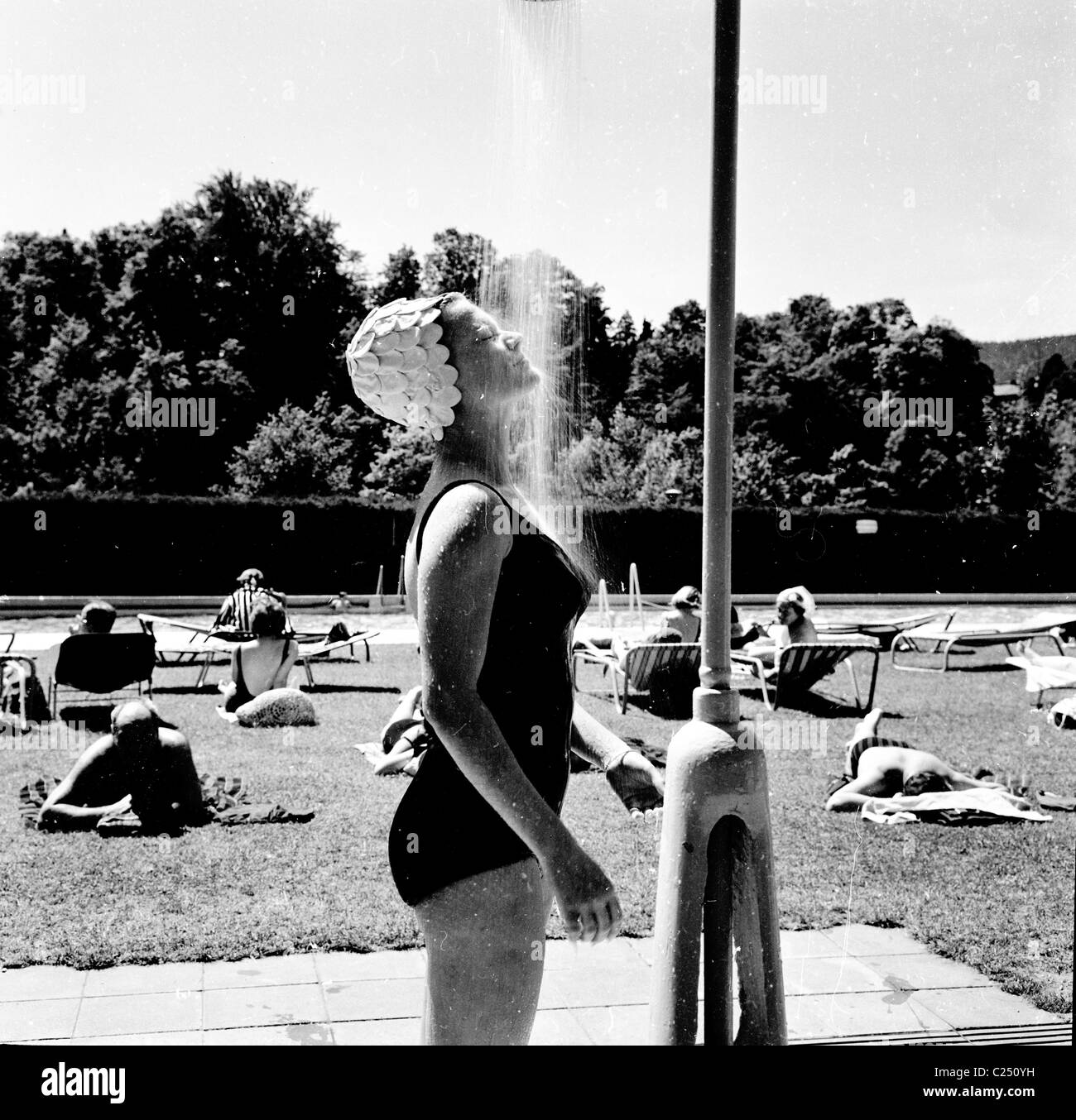 Deutschland der 1950er Jahre.  Weibliche Schwimmer mit Blütenblatt geformte Swimcap Duschen im Freibad Berthold schlecht, Baden-Baden. Stockfoto