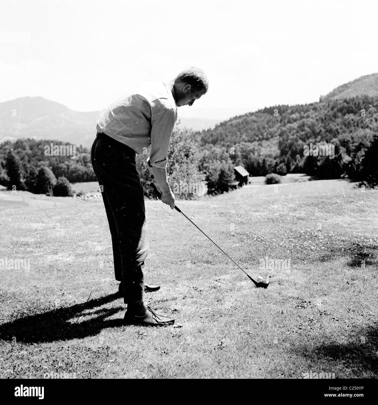 Deutschland der 1950er Jahre.  Männlichen Golfer am Abschlag mit Holzknüppel Adressierung den Ball auf dem Golfplatz in Baden-Baden. Stockfoto