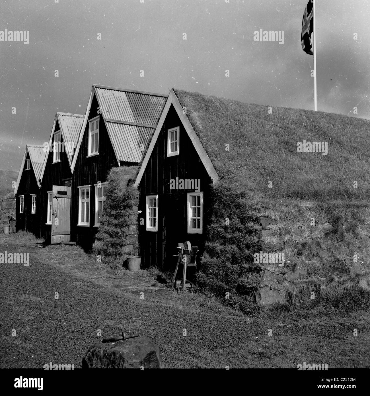 1950er Jahre, historica, eine Reihe von Holzhütten, einige mit Wellblech und eine mit Rasen auf dem Dach im Vordergrund, Island. Stockfoto