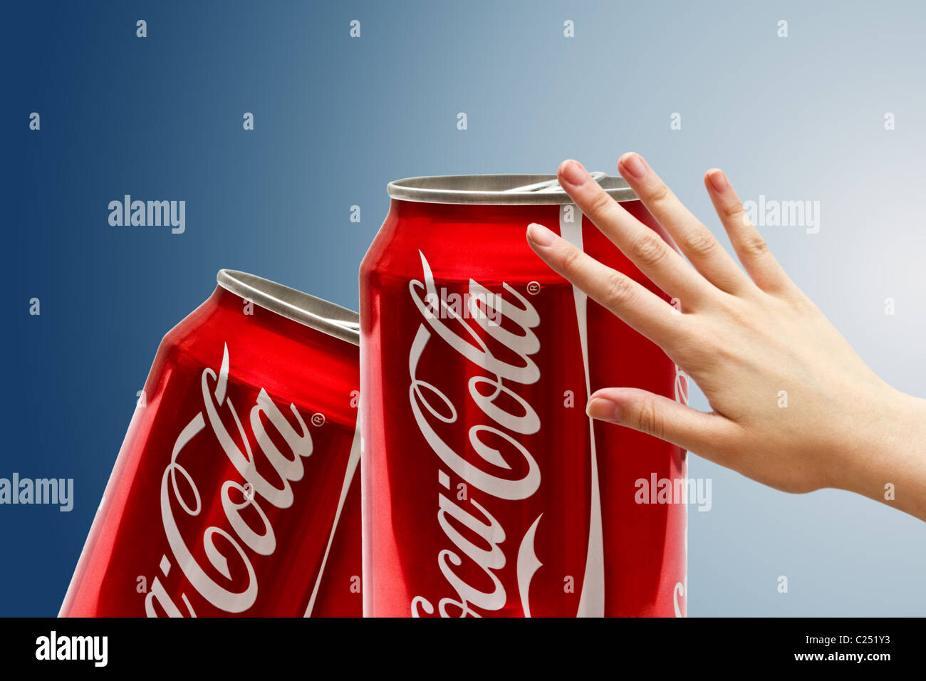 Coca-Cola können und hand Closeup auf blauem Hintergrund Stockfoto