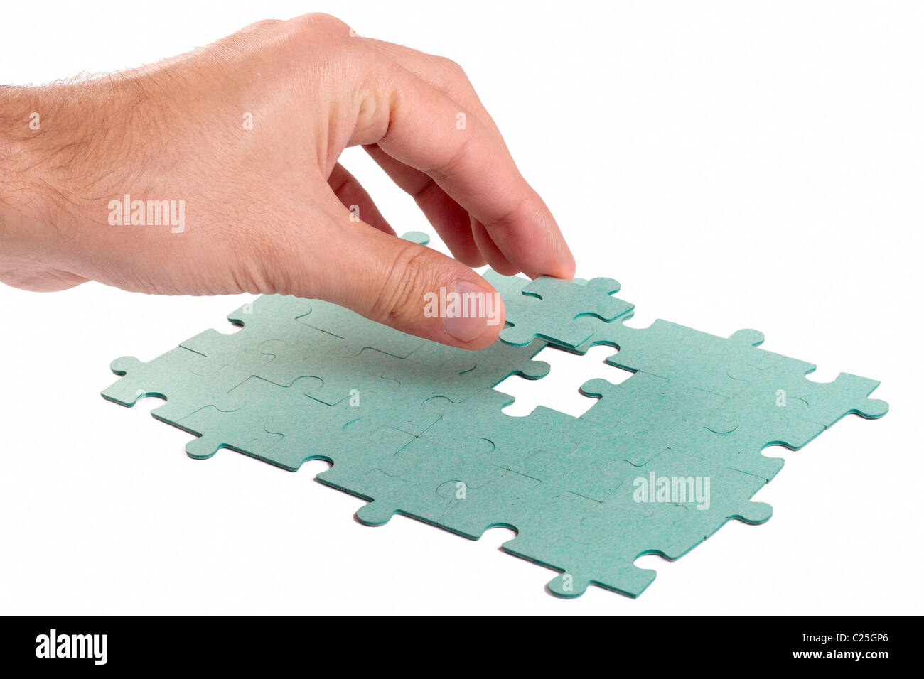 Hand, die fehlendes Stück Grün Puzzles in das Loch einsetzen Stockfoto